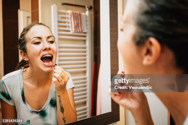 mujer limpiando sus dientes con cepillo interdental - women in suspenders fotografías e imágenes de stock