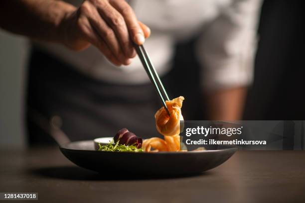 close-up van mannelijke chef-kok in restaurant siert de maaltijd - culinary tradition stockfoto's en -beelden