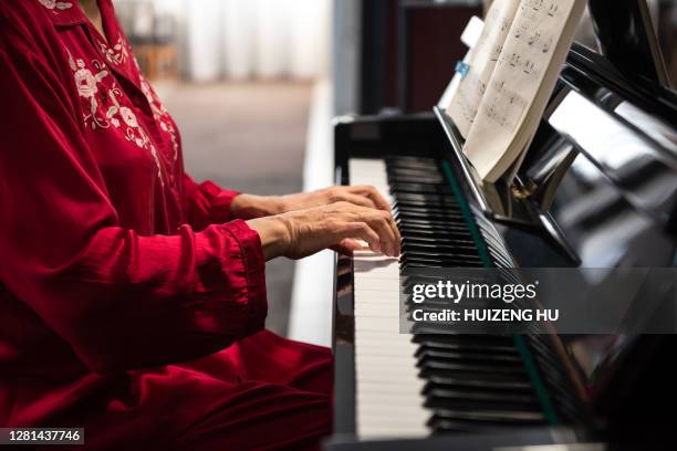 senior woman playing piano in her home. retirement woman - pianist stockfoto's en -beelden