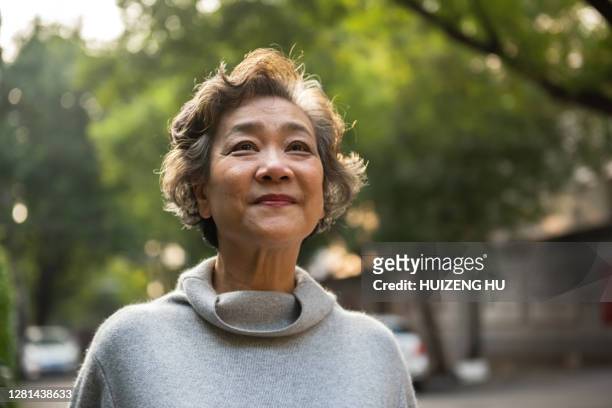 portrait of cheerful senior woman relaxing outdoor, standing on the road in the city - donne mature foto e immagini stock