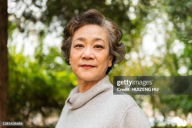 portrait of a senior woman smiling outdoor. happy senior woman standings outdoor - asia lady look at camera stock pictures, royalty-free photos & images