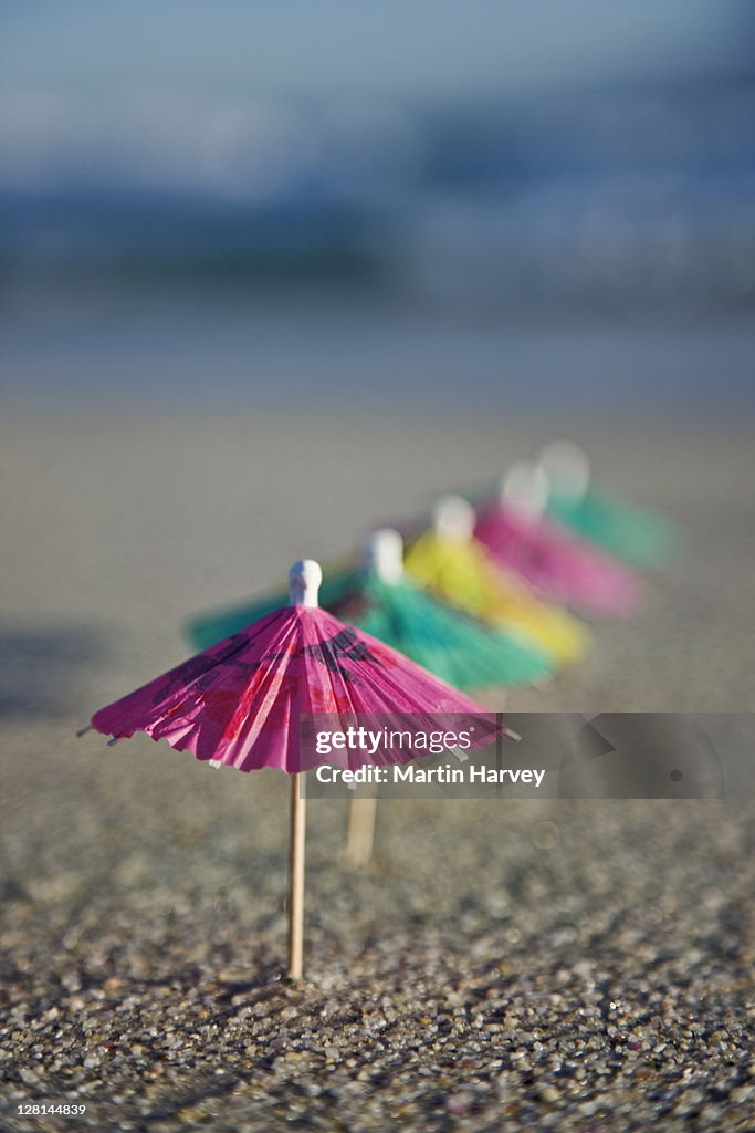 Cocktail umbrella's placed in the sand, close up