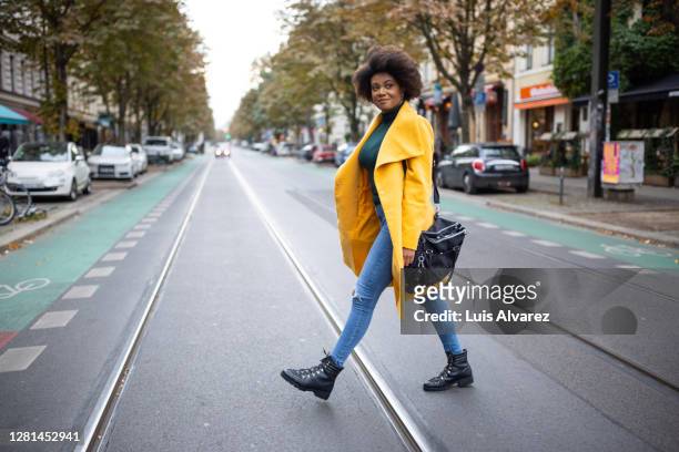 woman walking across the street - gehen stock-fotos und bilder