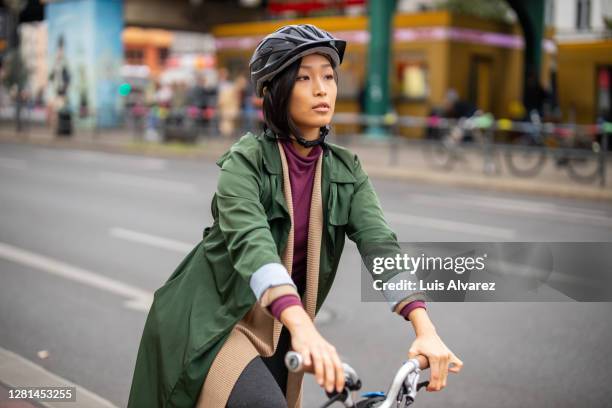 woman traveling in the city on a bicycle - sports helmet stock pictures, royalty-free photos & images