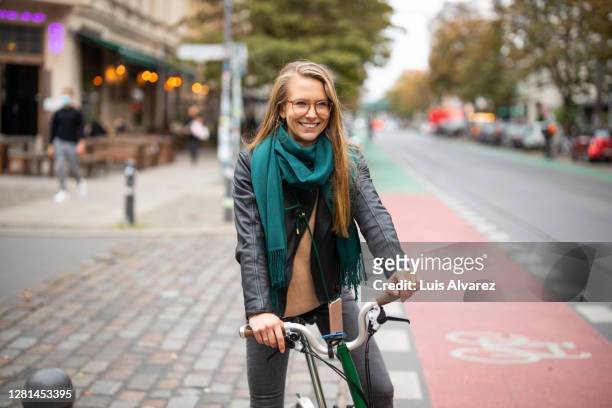 woman riding on a cycle through the city - german blonde stock pictures, royalty-free photos & images