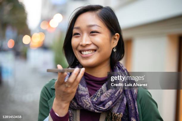 woman talking on speaker phone walking in the city - lady talking on the phone stock-fotos und bilder