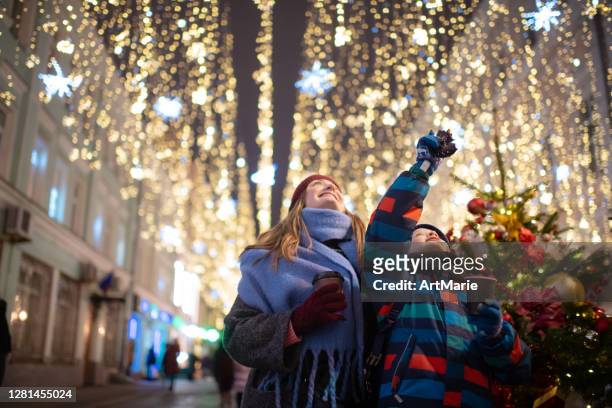 mutter und sohn auf einem weihnachtsmarkt - christmas tree lights stock-fotos und bilder