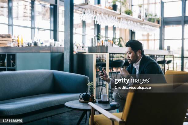 mens die aan podcast bij de de bedrijfslounge van de luchthaven luistert - airport lounge luxury stockfoto's en -beelden