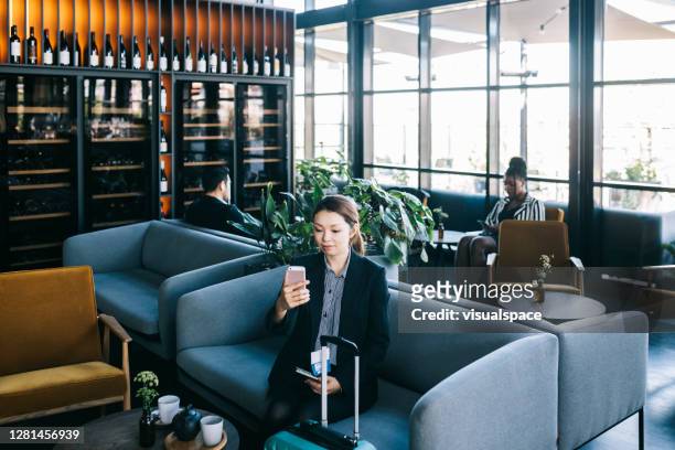 aziatische onderneemster op een videovraag bij de luchthaven - airport lounge luxury stockfoto's en -beelden