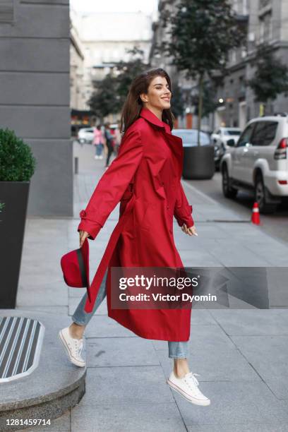 happy brunette in the trendy red raincoat - fashion street style stockfoto's en -beelden