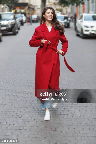 smiling red dressed woman walks down the street - red coat stock pictures, royalty-free photos & images