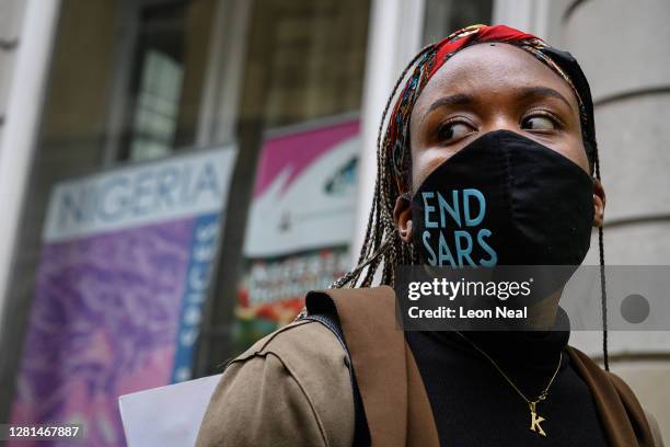 Woman wearing an "END SARS" protective face mask speaks with the police outside the Nigerian Consulate during a demonstration on October 21, 2020 in...