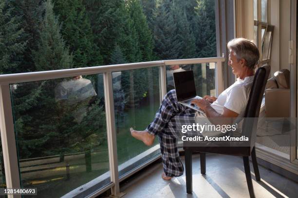man relaxes on sunlit deck in morning - terrace british columbia stock pictures, royalty-free photos & images