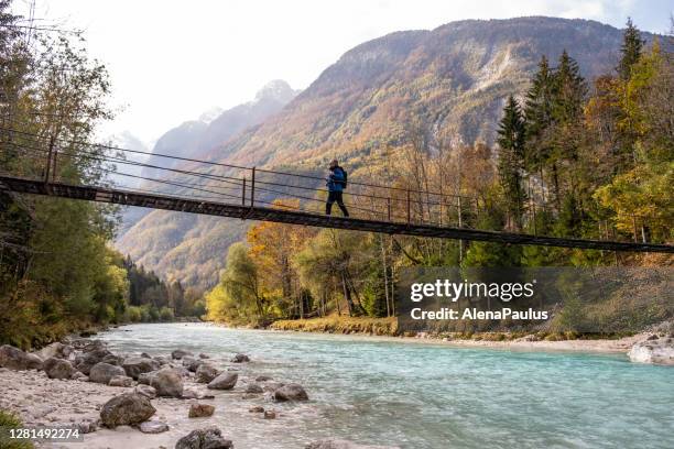 senior man walking on the suspension bridge over the soča river - slovenia hiking stock pictures, royalty-free photos & images