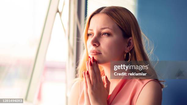 attractive business woman praying in office - triste bíblia imagens e fotografias de stock