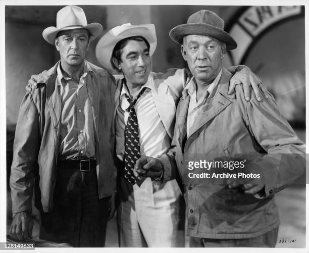 Anthony Quinn with his arms around Gary Cooper and Ward Bond in a scene from the film 'Blowing Wild', 1953.
