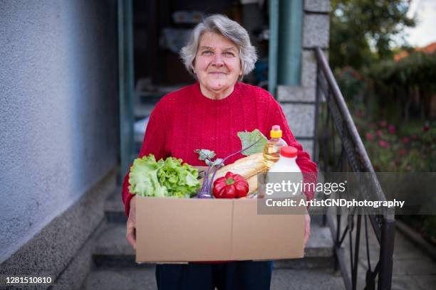 porträt der glücklichen seniorin mit erhaltener kiste mit nahrung während der pandemie. - supermarket help stock-fotos und bilder