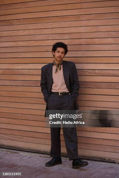 portrait of a handsome elegantly dressed young man standing facing camera with his hands in his pockets - facing camera professional outdoor stockfoto's en -beelden