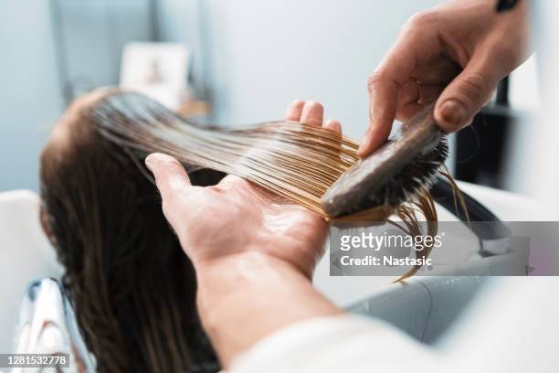 hairdresser brushing an washing woman's hair in hairdresser salon on a sink - brush in woman's hair imagens e fotografias de stock