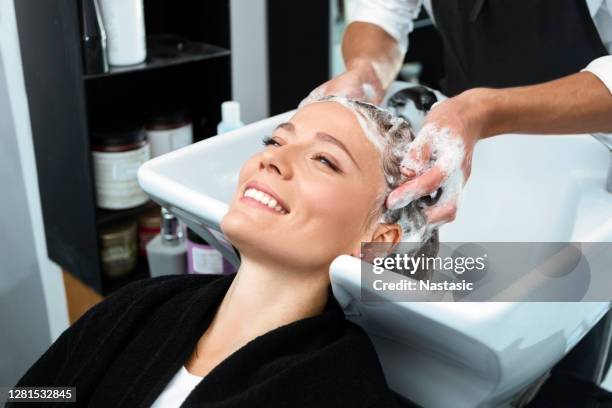 friseur waschen lächelnde frau haare in friseursalon - washing hair stock-fotos und bilder