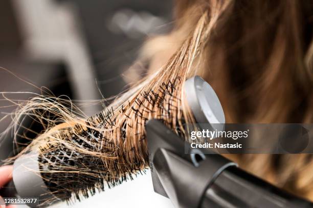 mujer joven en una peluquería, peluquero usando secador de pelo - cepillar el cabello fotografías e imágenes de stock