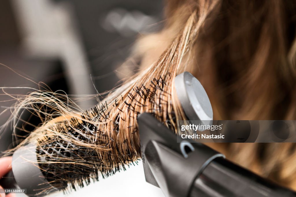 Giovane donna in un parrucchiere, parrucchiere che usa asciugacapelli