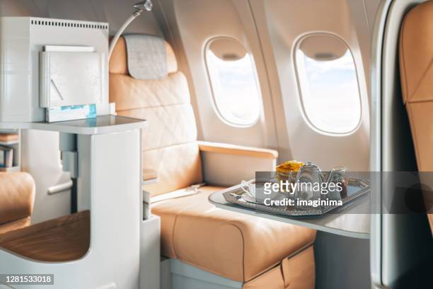 first class airplane seat with tray of food - seat stock pictures, royalty-free photos & images