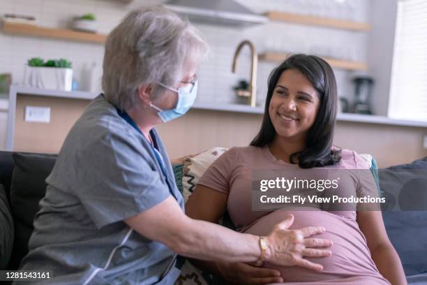 arzt besucht ethnische schwangere in ihrem haus - midwifery stock-fotos und bilder