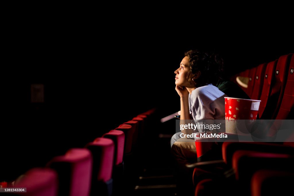 Young woman enjoying watching movie at the cinema