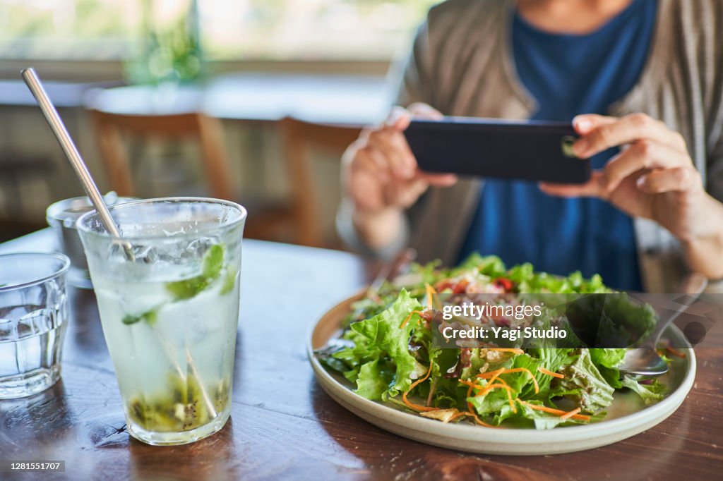 Woman using smartphone to photograph her food at a vegan cafe