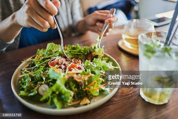 japanese woman eating a vegan lunch at a vegan cafe - tipo di cibo foto e immagini stock