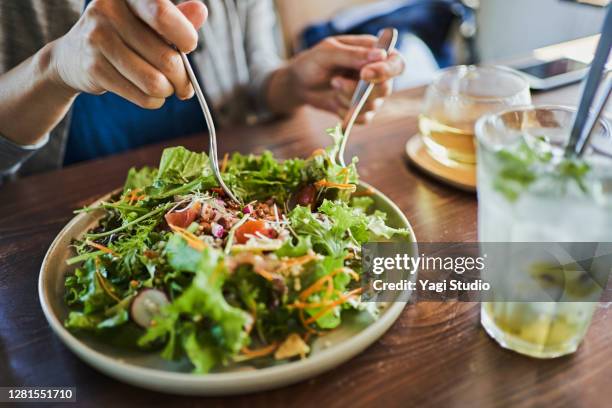 japanese woman eating a vegan lunch at a vegan cafe - veganist stockfoto's en -beelden