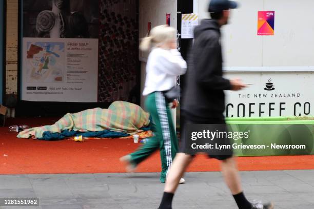 Pedestrians walk past a homeless person rough sleeping on High Street in central Auckland on October 17 the day of the general election. New...