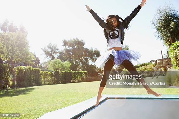 pre-teen girl (10-12) jumping on trampoline - 12 13 jaar stockfoto's en -beelden