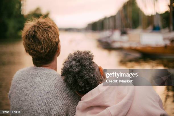 rear view of senior woman resting head on friend's shoulder during sunset - head on shoulder stock pictures, royalty-free photos & images