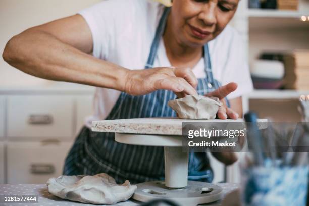 senior woman kneading clay in bowl shape at workshop - craft stock pictures, royalty-free photos & images
