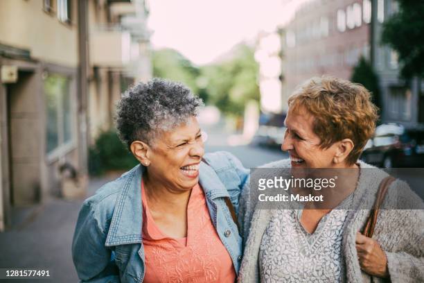 cheerful wrinkled female talking to friend in city - nur erwachsene stock-fotos und bilder