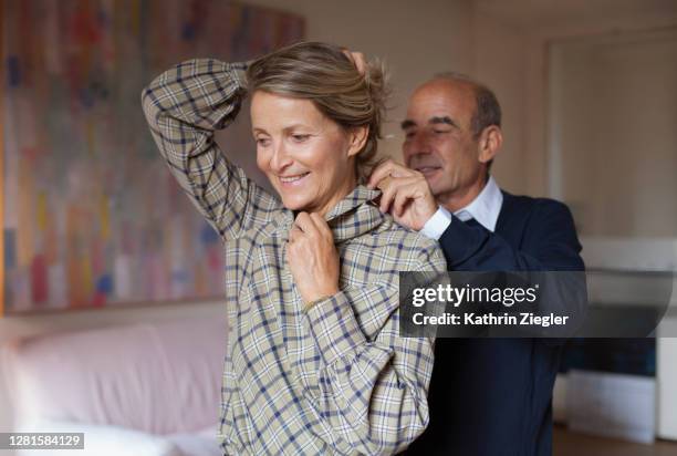 man helping woman to button up the collar of her blouse - help getting dressed stock pictures, royalty-free photos & images