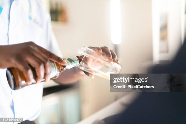 close up barman pouring bottle of beer into a glass - beer luxury stock pictures, royalty-free photos & images