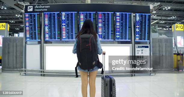 asian woman passenger wearing blue jeans drag the wheeled suitcase inside the passenger building - lost luggage stock pictures, royalty-free photos & images