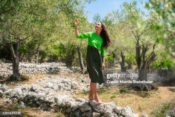 frau in grünem kleid in olivenhain auf steinen balancieren - frau fotografías e imágenes de stock