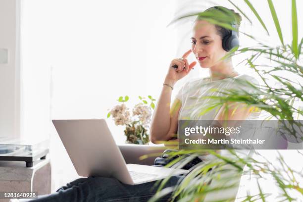 business frau im homeoffice mit laptop - blick in die kamera - modern frau business stockfoto's en -beelden