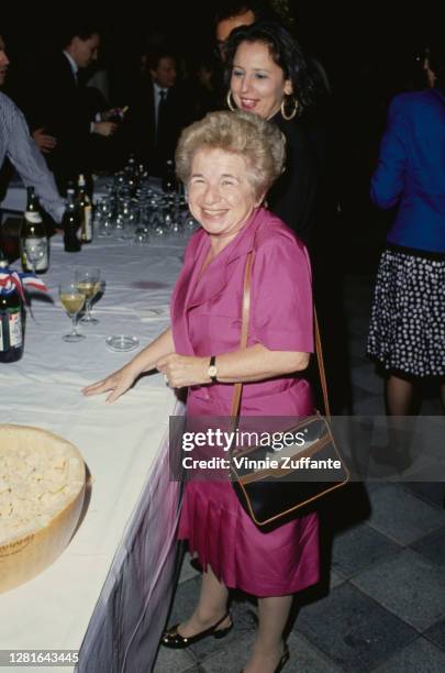 German-born American sex therapist Ruth Westheimer wearing a pink dress, and carrying a handbag, standing beside a table with drinks on it, at an...