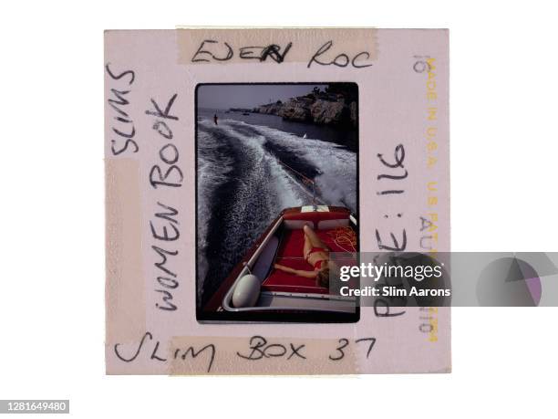 Woman sunbathing in a motorboat as it tows a waterskiier, in the sea off the Hotel du Cap-Eden-Roc in Antibes on the French Riviera, August 1969.