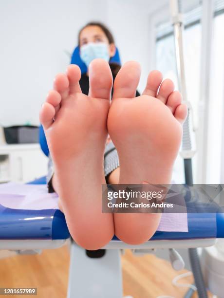 view of the bare feet of a teenage girl at the podiatrist consultation - plantaire wrat stockfoto's en -beelden