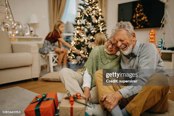 senior man and senior woman exchange christmas gifts - christmas elderly stock pictures, royalty-free photos & images