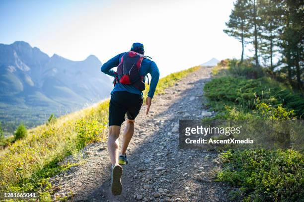 sendero hombre corre a lo largo de la cresta de la montaña al amanecer - carrera de campo través fotografías e imágenes de stock
