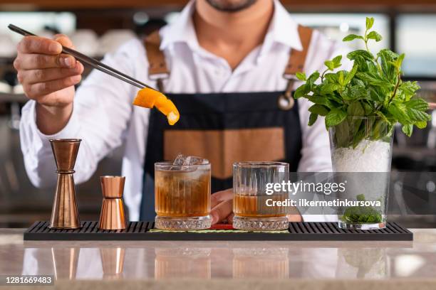 bartender, der zitronenschale in einem getränk hinzufügt - bartender mixing drinks stock-fotos und bilder