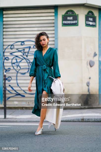 Maria Decremps wears a green double breasted lustrous silky dress, earrings, snake print pointy gray shoes, outside Paco Rabanne, during Paris...