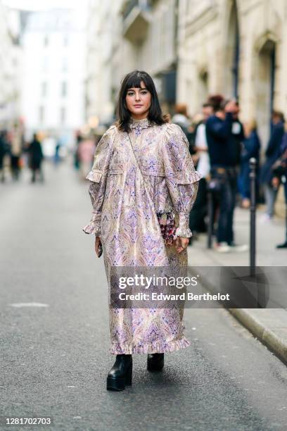 Maria Bernad wears a large ruffled floral print dress, a shiny sequined bag, black high heels platform leather boots, outside Paco Rabanne, during...